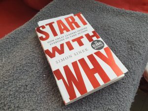 simon sineks book start with why on a grey blanket